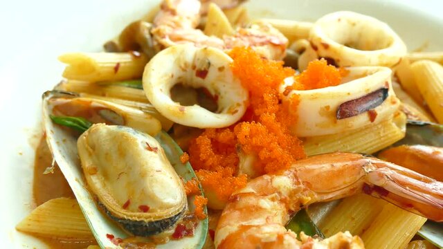 Penne tom yum seafood in white plate