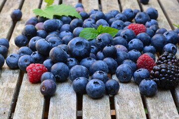 Blueberries, raspberries and peaches on a wooden table