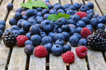 Blueberries, raspberries and peaches on a wooden table