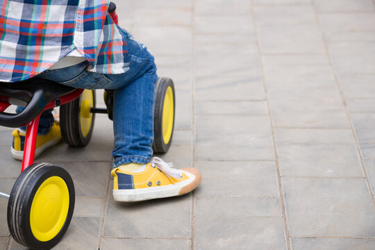 Small toddler boy riding his toy bicycle on street concrete. Child learning to ride a bike.