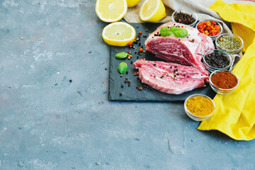 Fresh raw meat with herbs,spices  on dark rustic background, top view, place for text. Cooking concept.