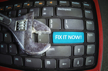 Fix it now blue button on a dirty computer keyboard with wrench tool. Fish eye effect.