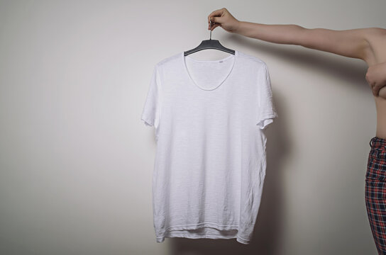 Girl with naked torso holding a white T-shirt in her hand. Branding Mock-Up.