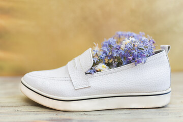 Women's white shoes and white and purple flowers inside