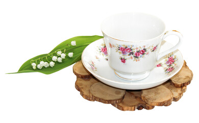 A bouquet of fresh Sprig of lily of the valley near a tea pair from a saucer cup on a juniper stand