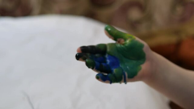 The boy draws paints in the house at the table.