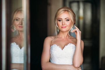  Portrait of a bride in a wedding dress. The bride dresses in the hotel.