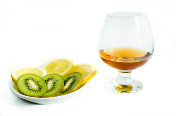 a glass of Cognac with assorted kiwi and lemon on white background