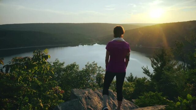 Woman stands on the mountain rocks and admiring a buatiful view