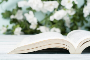 Open hardback book on wooden table and natural background. Back to school. Copy space for ad text.