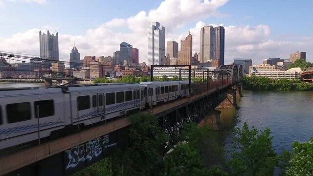 PITTSBURGH - Circa May, 2017 - A daytime aerial establishing shot of the early evening Pittsburgh skyline as a subway train travels in the foreground.	