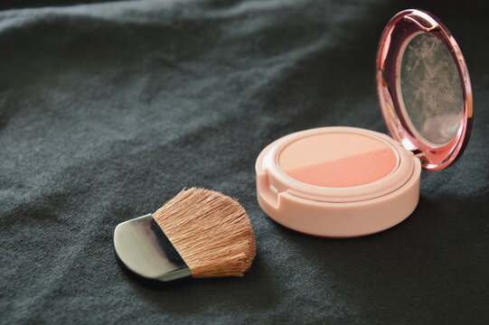 blusher powder cartridges and brush on black fabric background