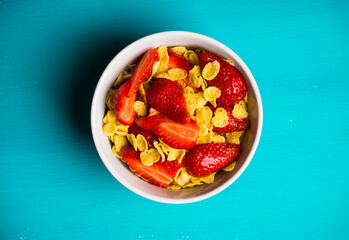 Corn flakes with fresh strawberry in bowl on the rustic background. Shallow depth of field.