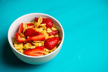 Corn flakes with fresh strawberry in bowl on the rustic background. Shallow depth of field.
