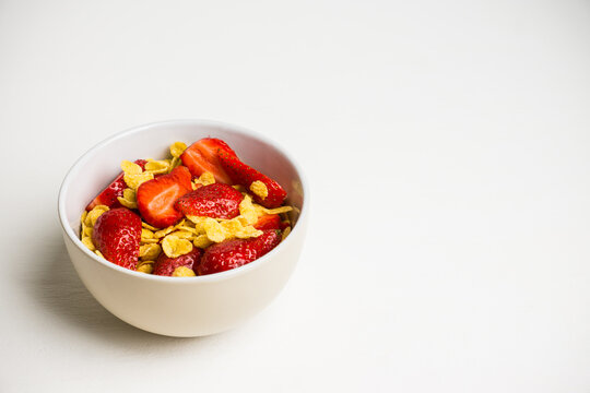 Corn flakes with fresh strawberry in bowl on the rustic background. Shallow depth of field.