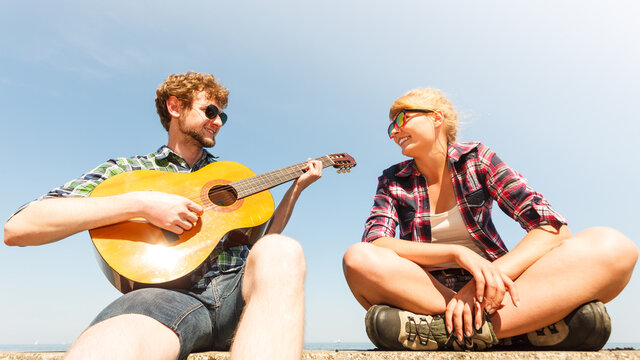 Young man hipster playing guitar for woman.