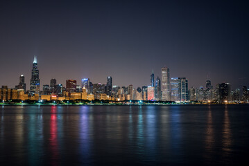 Nightime Skyline of Chicago, a haze behind the bright city lights and the colorful reflections in...