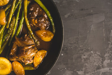 Grilled pork with asparagus and peaches in pan on the black background. Shallow depth of field. Toned image.