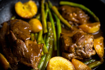 Grilled pork with asparagus and peaches in pan on the black background. Shallow depth of field.