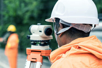 worker use surveyor’s telescope at new road construction site