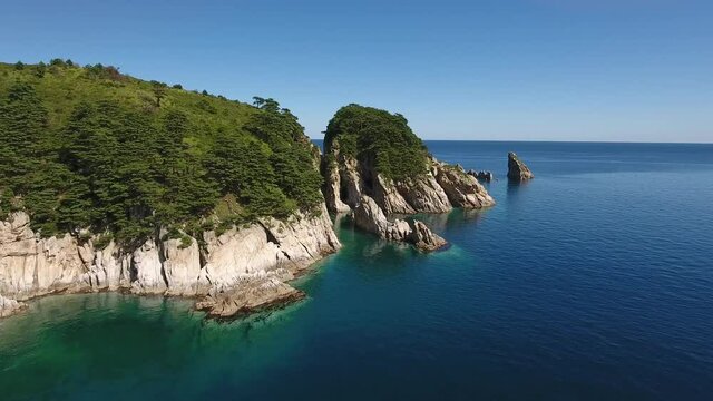 Kekura rocks from water forward flight over the cape. Far East Marine Reserve, Primorsky Krai Vladivostok Russia. Unique National park Japan Sea ocean. Aerial Helicopter Drone. Summer day. 4k