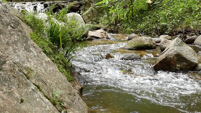 Slow motion rushing waterfall in the mountains with tropical forest. Beautiful nature background. 