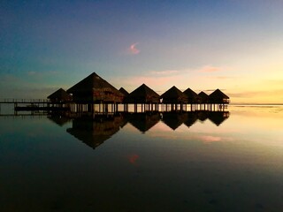 Fototapeta premium Beautiful view on Moorea and the overwater bungalows of a luxury resort during sunset at the beach of Punaauia