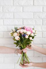 Fototapeta premium Delivery of a floral workshop. The customer receives his order-a bouquet of pink roses and wild flower. Hand courier pass flowers to the buyer