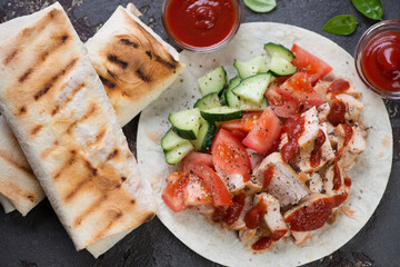Top view of shaurma or shawarma with roasted chicken, vegetables and lavash