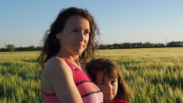 Happy family in a field of wheat. Mom and daughter in the field at sunset.