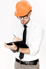 Portrait of young construction engineer in orange helmet with folder on white background