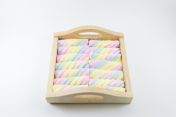 Colorful candy in wood tray on white background.