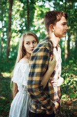 Young beautiful woman with long blond hair standing behind her boyfriend embracing him