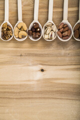 Nuts in a wooden spoons on a  wooden table.