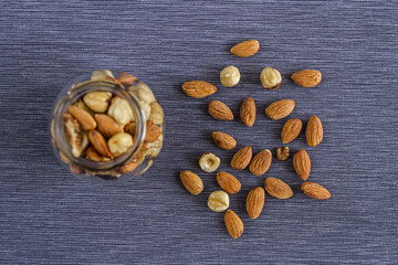 Appetizing nuts of walnuts, almonds and hazelnuts in a glass beautiful vase and on a gray textile background for a healthy snack.