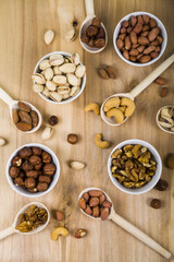 Nuts in a wooden spoons and bowls on a  wooden table.