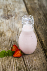 Smoothies and ripe strawberry on a wooden table.