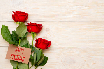 happy birthday greeting text on craft paper card with red roses and copy space