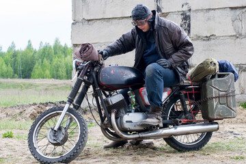 Obraz na płótnie Canvas A post apocalyptic man on motorcycle near the destroyed building