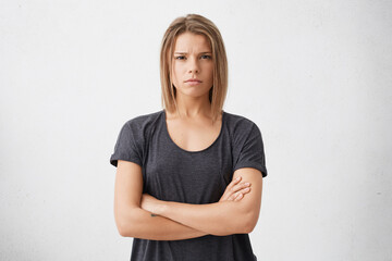Waist up shot of beautiful irritated young woman with bob haircut holding her arms crossed, having...