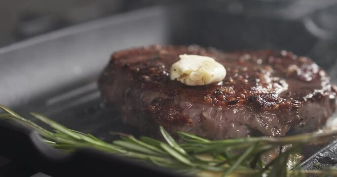 Slide slow motion shot of flip rib eye steak with herbs on grill pan, 4k 60fps prores footage