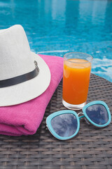 Summertime orange juice hat and sunglasses relax near swimming pool