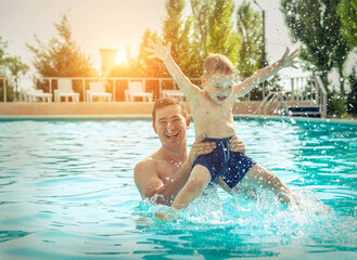Father and son funny in  water pool under sun light at summer da