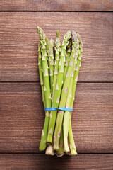 Heap of green asparagus on brown wooden table