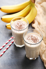 Cocktail with bananas in glasses on grey wooden table