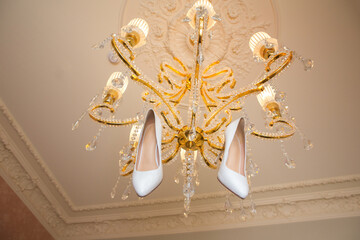 white wedding shoes hanging on the chandelier