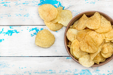 Bowl with potato chips on the wooden table. Top view.