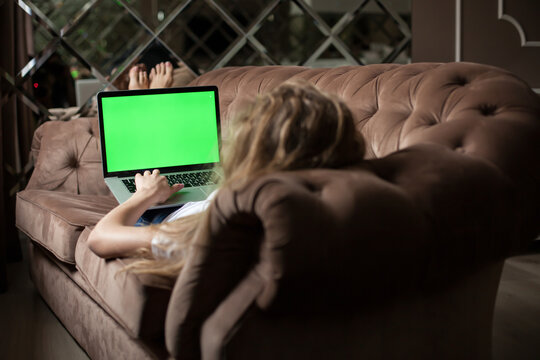 Blonde lying on the sofa with the laptop. Green screen.