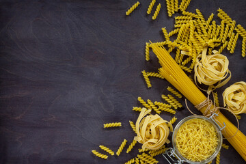 Different kinds of pasta on the kitchen wooden table. The concept of Italian food. Top view, copy space.