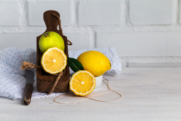 Whole lemon, lime and lemon halves on white table against white loft background.
